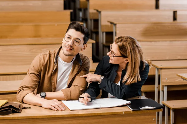 Insegnante universitaria donna seduta alla scrivania con studente maschio durante l'esame in aula — Foto stock