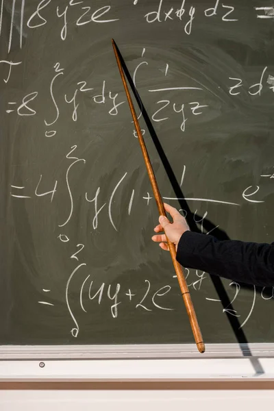 Обрізаний вид жінки-вчителя з дерев'яним вказівником, що пояснює математичні рівняння в класі — стокове фото