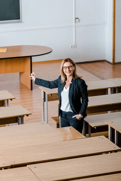 Sorridente professora universitária com a mão estendida em pé em sala de aula — Fotografia de Stock