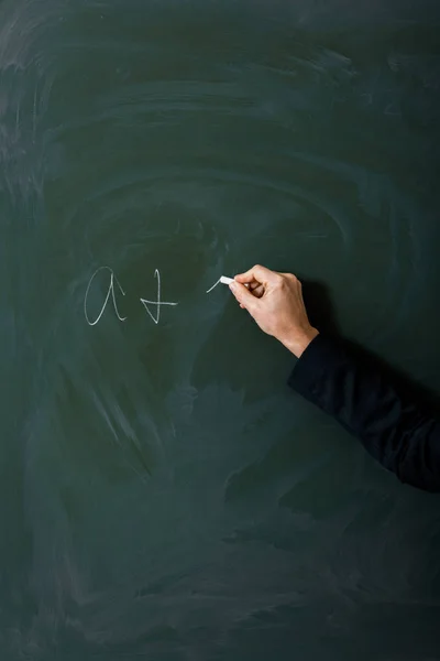 Partial view of female teacher writing equation on green chalkboard — Stock Photo