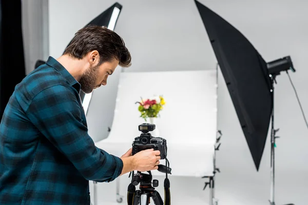 Young photographer photographing beautiful flowers in professional photo studio — Stock Photo