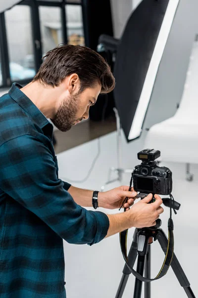 Handsome young man working with professional photo camera in studio — Stock Photo