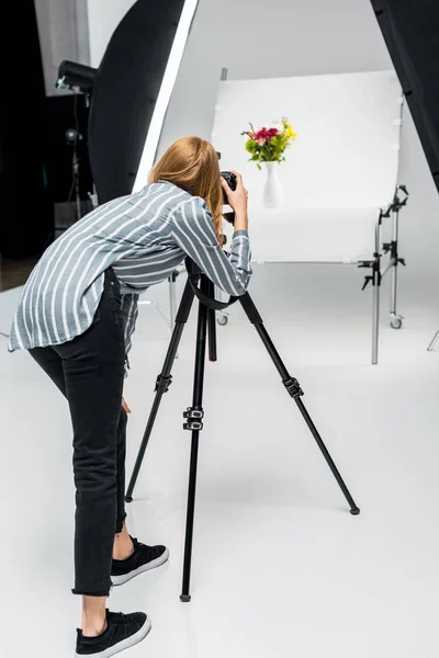 Vista posteriore della giovane donna che spara bellissimi fiori in studio fotografico professionale — Foto stock
