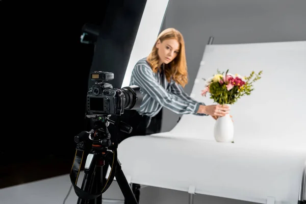 Close-up vista da câmera fotográfica e fotógrafo feminino organizando flores em estúdio — Fotografia de Stock