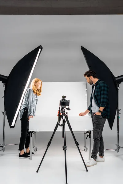 Visão lateral de jovens fotógrafos que trabalham com equipamentos profissionais no estúdio de fotografia — Fotografia de Stock