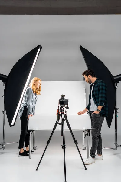 Vista laterale di giovani fotografi che lavorano con attrezzature professionali in studio fotografico — Foto stock