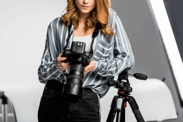 Cropped shot of beautiful young woman using professional photo camera in studio — Stock Photo