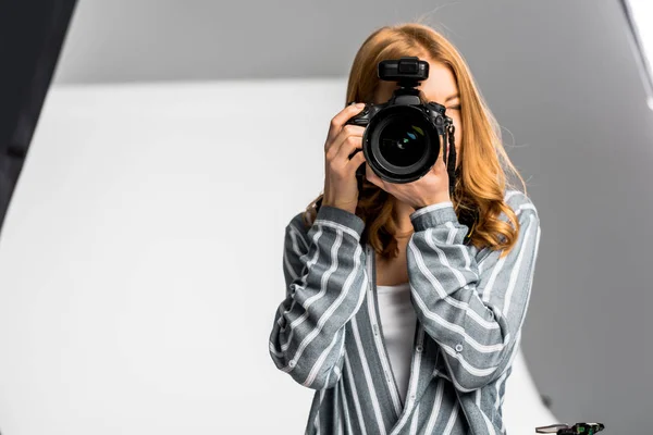 Bela jovem fotógrafo fotografar com câmera profissional em estúdio — Fotografia de Stock