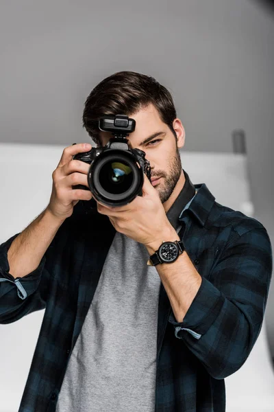 Guapo joven fotógrafo masculino disparando con cámara profesional - foto de stock