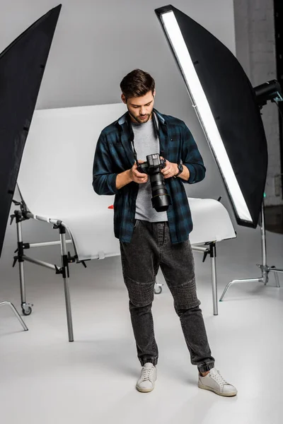 Vollansicht des hübschen professionellen jungen Fotografen mit der Kamera im Fotostudio — Stockfoto