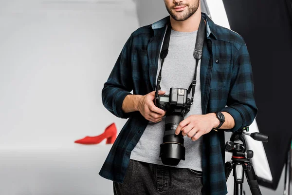 Tiro recortado de fotógrafo jovem profissional segurando câmera no estúdio de fotos — Fotografia de Stock