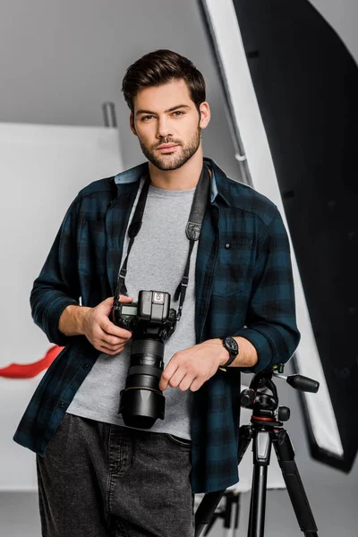 Jovem fotógrafo profissional bonito olhando para a câmera no estúdio de fotos — Fotografia de Stock