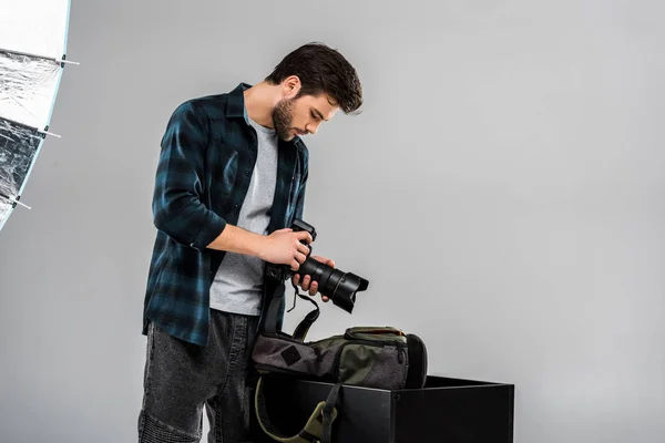 Beau jeune photographe tenant appareil photo professionnel en studio — Photo de stock