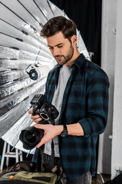 Schöner junger Fotograf mit professioneller Fotoausrüstung im Studio — Stockfoto
