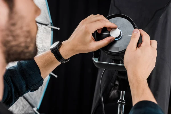 Cropped shot of young man working with professional lighting equipment in photo studio — Stock Photo