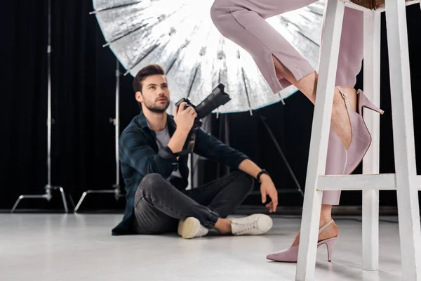 Tiro recortado de fotógrafo sentado e fotografando elegante modelo feminino em estúdio — Fotografia de Stock