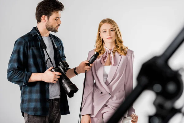 Jovem fotógrafo segurando câmera e medidor de luz enquanto trabalhava com modelo em estúdio — Fotografia de Stock