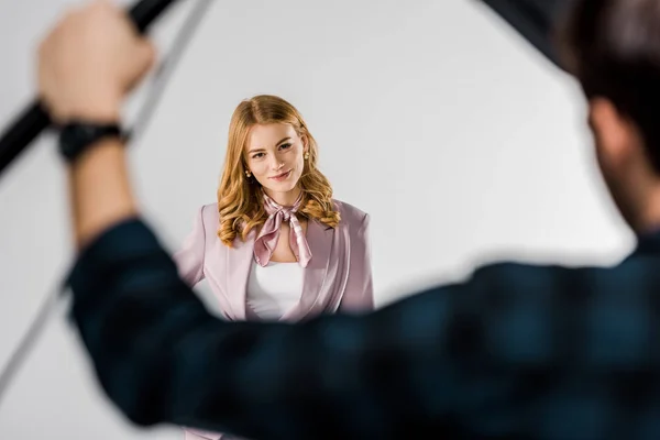 Tiro recortado de fotógrafo trabalhando com equipamentos de iluminação, enquanto modelo feminino posando em estúdio — Fotografia de Stock