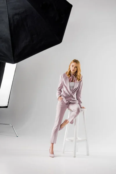 Beautiful young model in pink suit posing in photo studio — Stock Photo