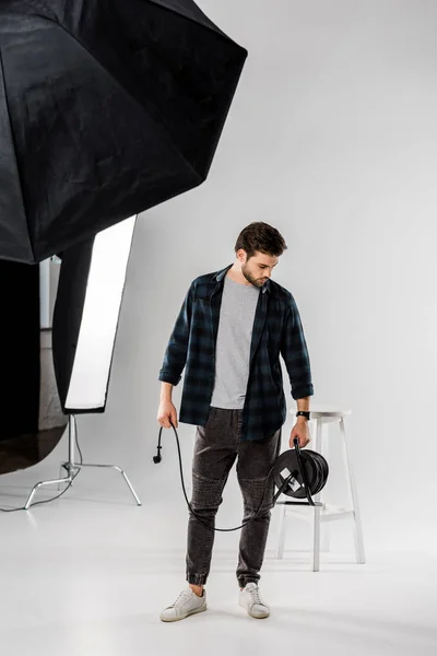 Jeune homme travaillant avec du matériel photo dans un studio professionnel — Photo de stock