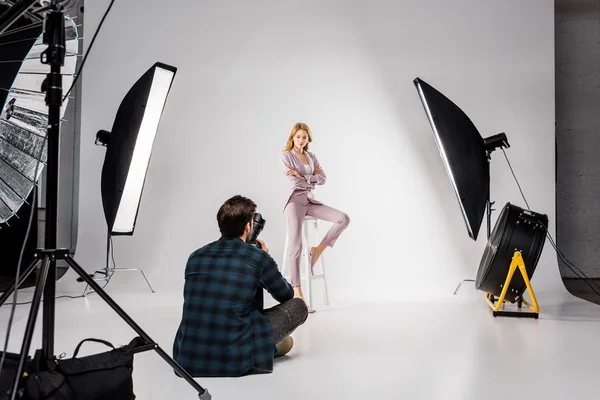 Rückansicht junger Fotograf beim Shooting eines schönen weiblichen Modells im Studio — Stockfoto