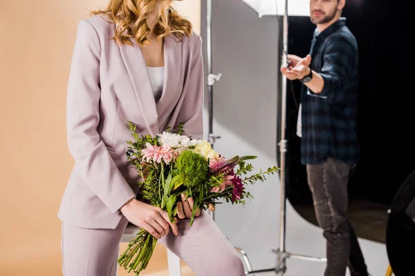 Cropped shot of photographer and young female model with bouquet of flowers in photo studio — Stock Photo