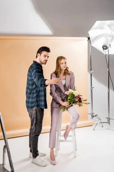Jeune photographe parler avec belle mannequin femme en studio photo — Photo de stock