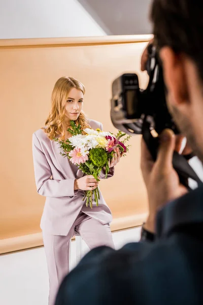 Обрізаний знімок фотографа, зйомка молодої жіночої моделі позує з квітами в фотостудії — стокове фото