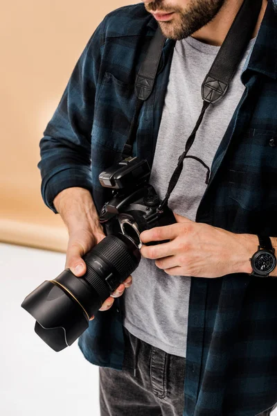 Tiro recortado de fotógrafo jovem segurando câmera de foto profissional em estúdio — Fotografia de Stock