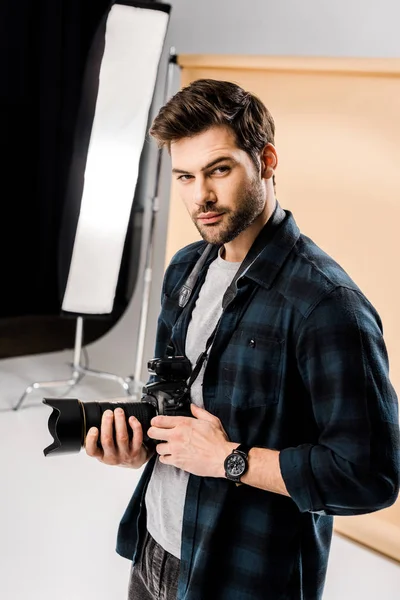 Handsome young photographer looking at camera in professional photo studio — Stock Photo