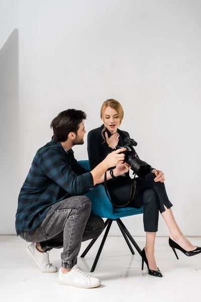 Jovem fotógrafo e belo modelo surpreso usando câmera de fotos juntos em estúdio — Fotografia de Stock