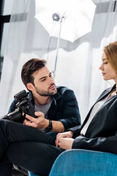 Young photographer and beautiful woman using camera together in photo studio — Stock Photo