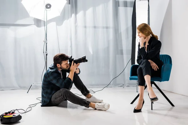 Young male photographer shooting beautiful model in studio — Stock Photo