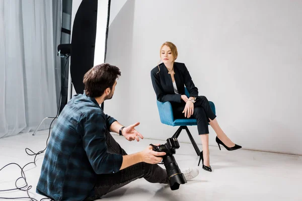 Photographer with camera and young model talking in photo studio — Stock Photo