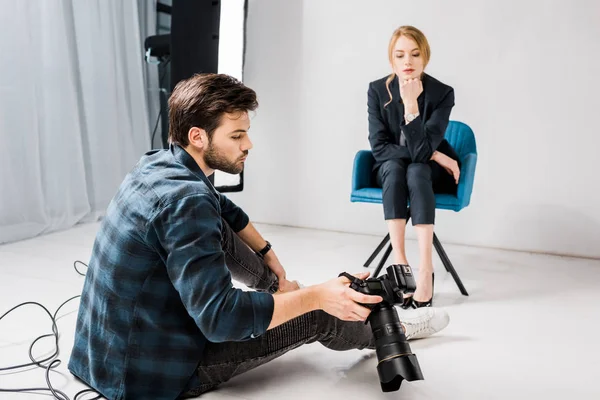 Young photographer showing camera to beautiful female model in photo studio — Stock Photo