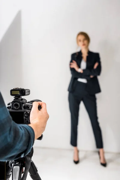 Обрезанный снимок фотографа с камерой, снимающий красивую молодую женщину в студии — стоковое фото