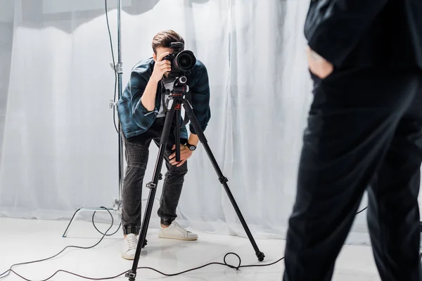 Cropped shot of young photographer shooting beautiful female model in photo studio — Stock Photo