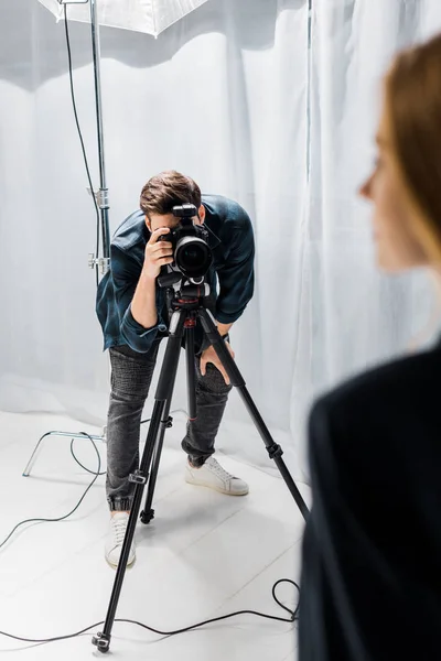 Tiro recortado de fotógrafo jovem atirando bela modelo feminina em estúdio — Fotografia de Stock