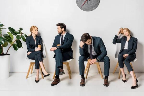 Collage de jóvenes empresarios sosteniendo café para ir y esperando en sillas en línea - foto de stock