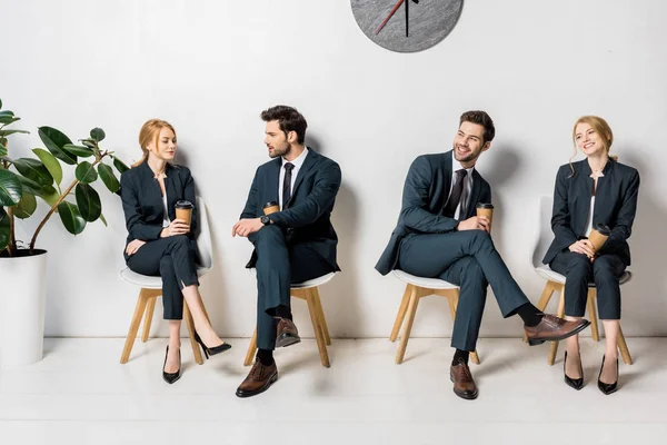 Collage of young business people holding paper cups and waiting on chairs in line — Stock Photo