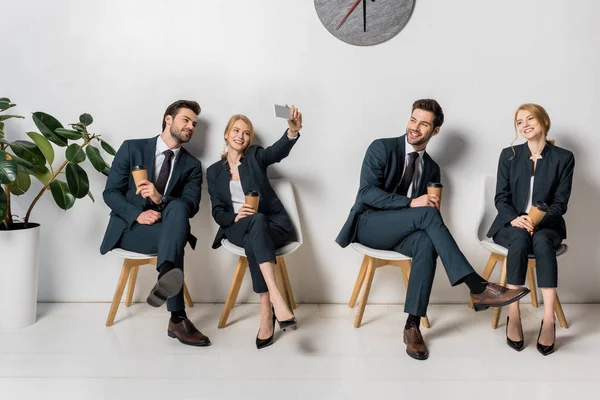 Collage de jóvenes empresarios sonrientes con teléfonos inteligentes y vasos de papel esperando en sillas en línea - foto de stock