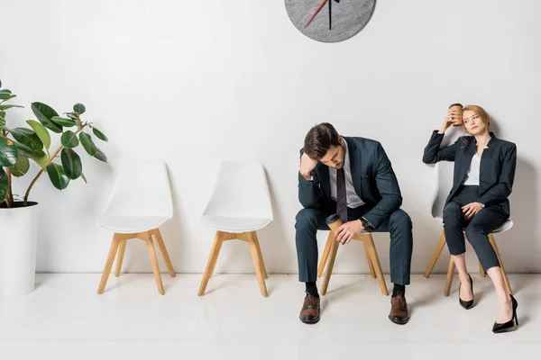 Aburrido gente de negocios cansada esperando en sillas en línea - foto de stock