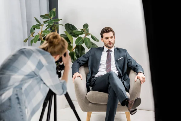 Young female photographer shooting handsome businessman in studio — Stock Photo