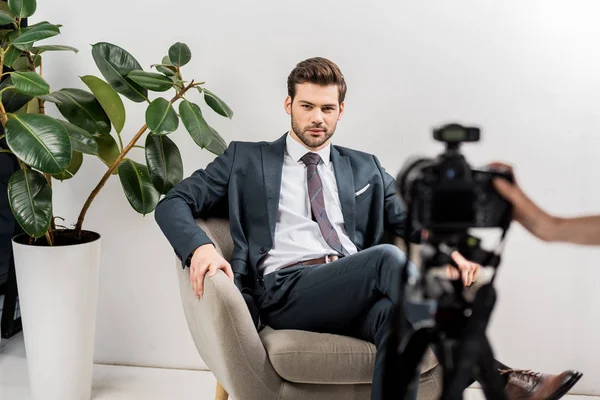 Recortado disparo de fotógrafo tomando fotos de hombre guapo en traje elegante en el estudio - foto de stock