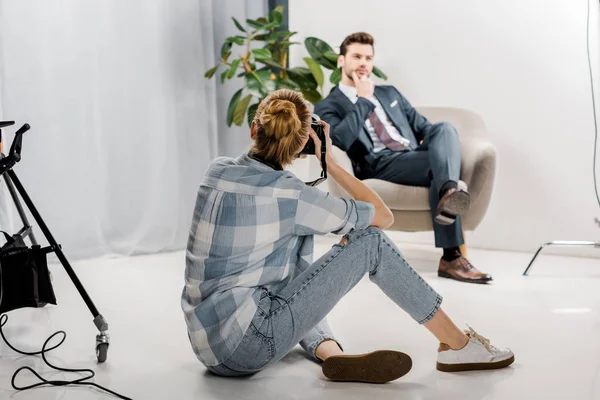 Young female photographer with camera photographing handsome male model in studio — Stock Photo