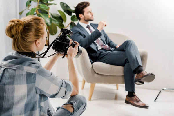 Vista posteriore di giovane fotografo donna fotografare bello uomo d'affari in studio — Foto stock