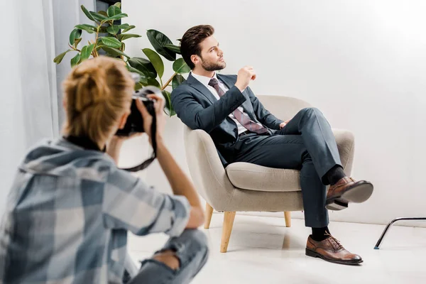 Young female photographer photographing handsome businessman in studio — Stock Photo