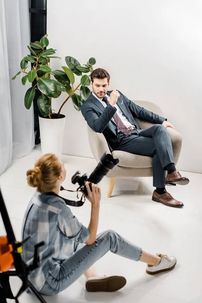 Vista ad alto angolo di giovane fotografo donna fotografare bell'uomo d'affari in studio — Foto stock