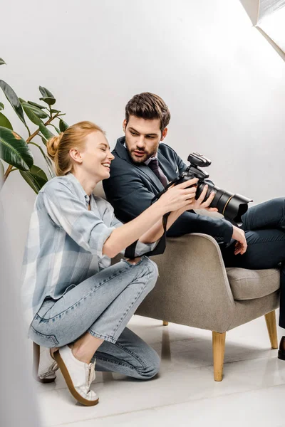 Souriant photographe femme et bel homme d'affaires en utilisant un appareil photo en studio photo — Photo de stock