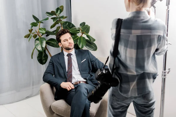 Back view of photographer with camera looking at handsome businessman in photo studio — Stock Photo